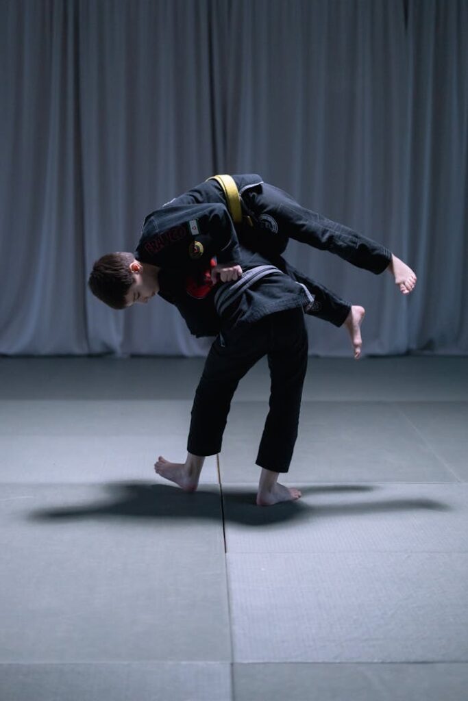 Two boys practicing a jiu jitsu move in a martial arts gym. Focus on youth fitness and combat sport skills.